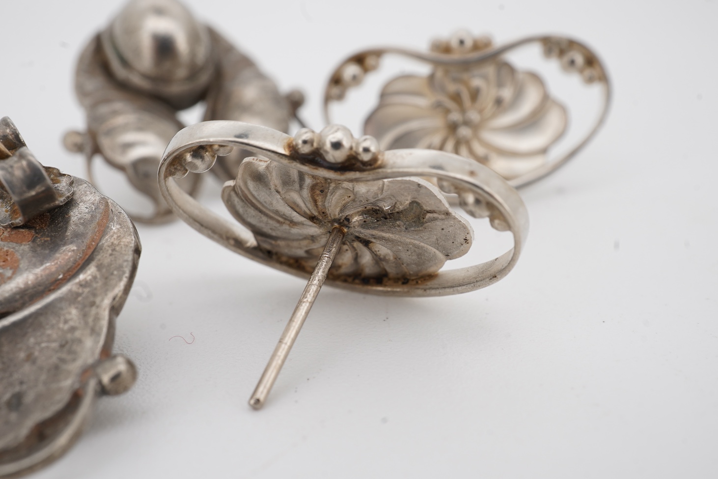 Two pairs of Georg Jensen sterling ear studs, one pair of leaf and berry design, 18mm and flower head form, design no. 52, lacking butterflies.